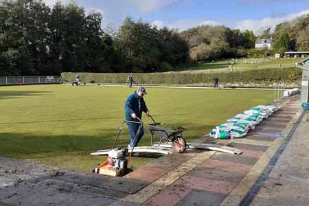 Person wheeling barrow off green 