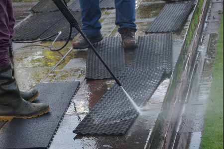 Person pressure washing a mat
